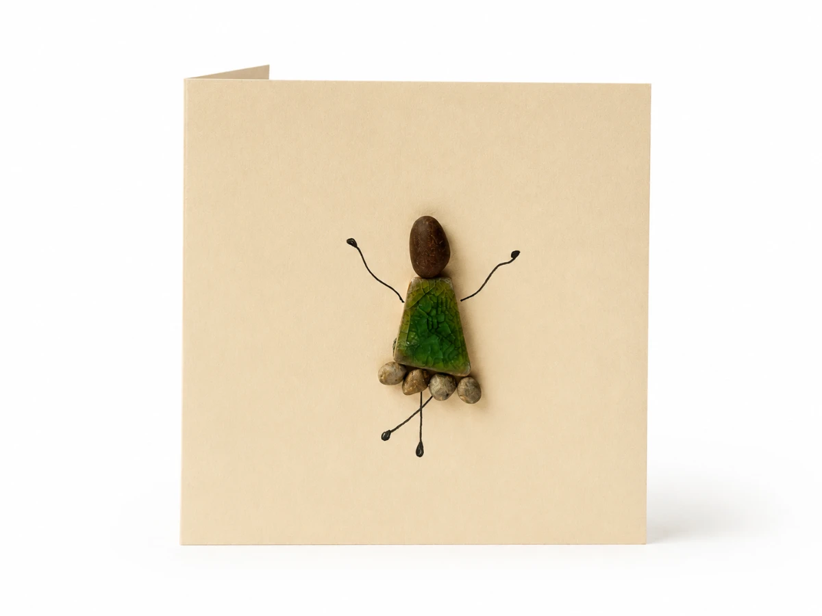 Cream handmade greeting card featuring a pebble doll with a green mosaic dress