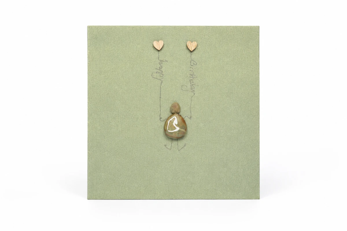 Green handmade greeting card featuring a pebble figure with two heart balloons