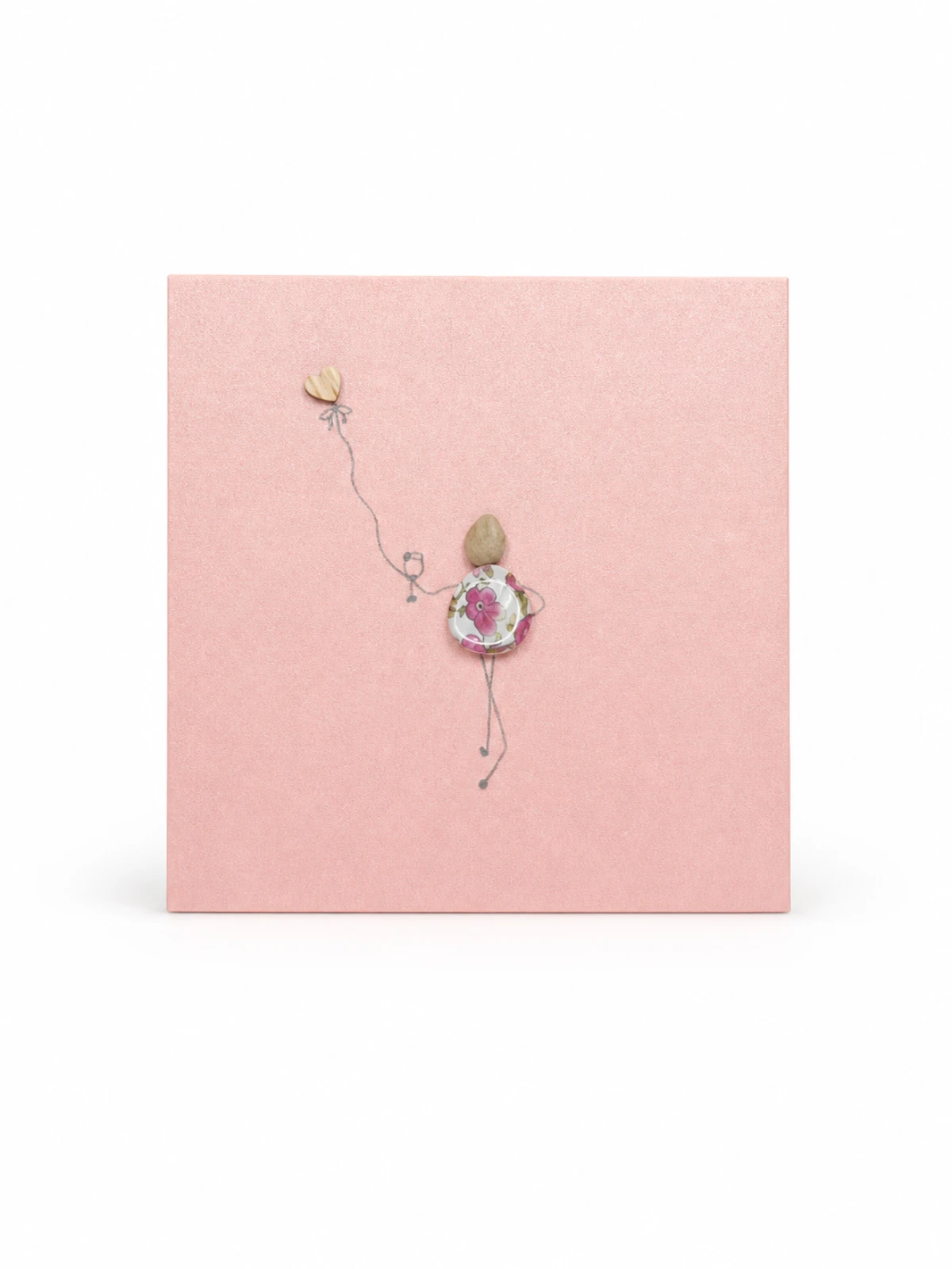 Pink handmade greeting card featuring a pebble figure with a floral dress and heart balloon