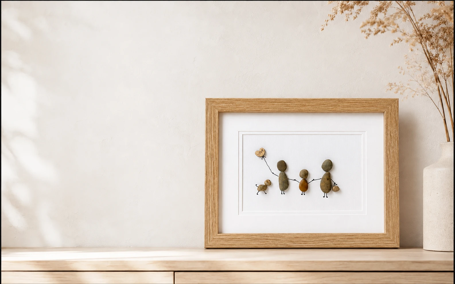 Personalised handmade pebble artwork of a family in a timber frame